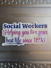 Sticker with text 'Social Workers Helping you live your best life since 1898' on a laptop surface