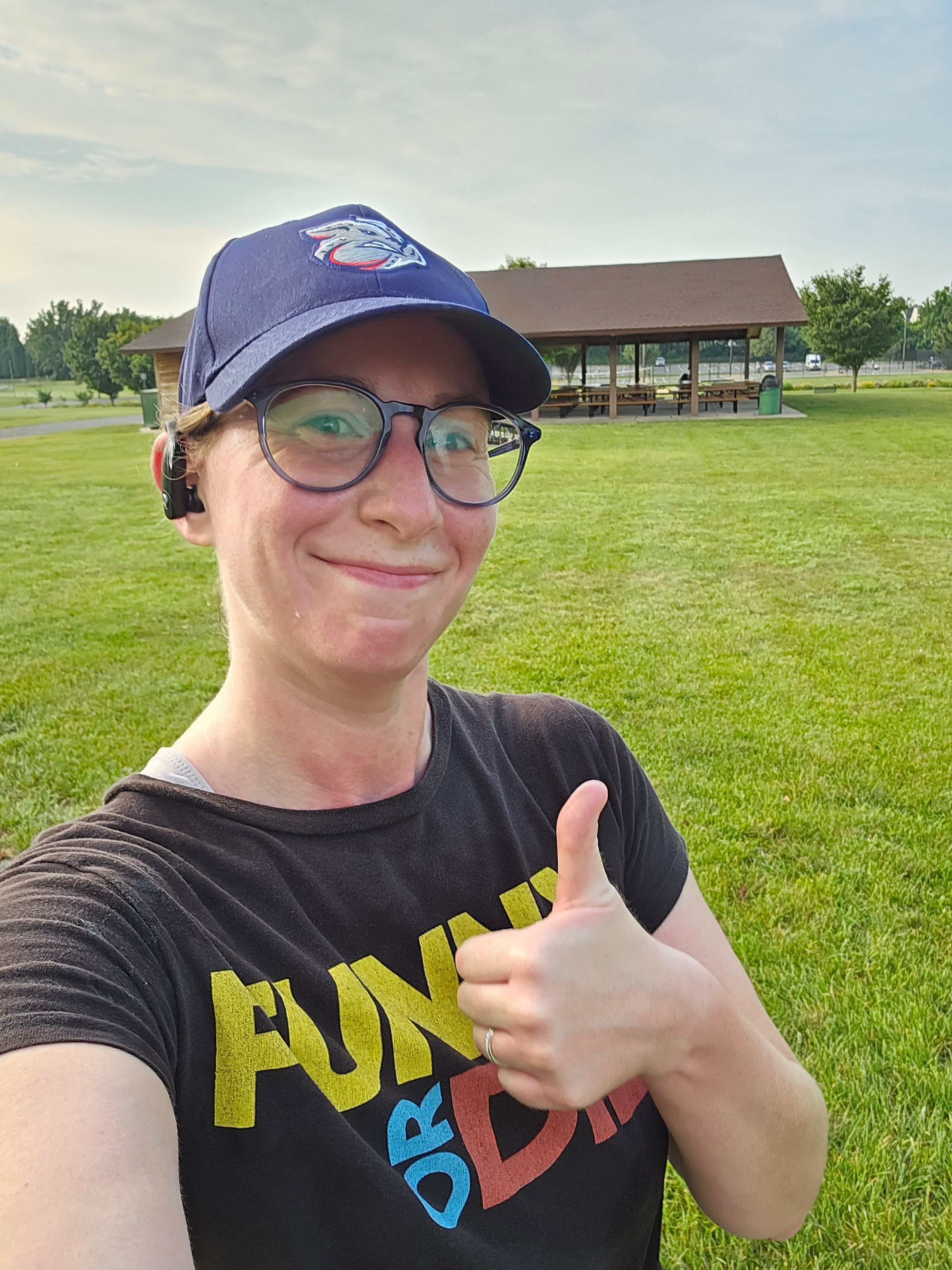 Person wearing a black t-shirt with colorful text and a navy cap outdoors.